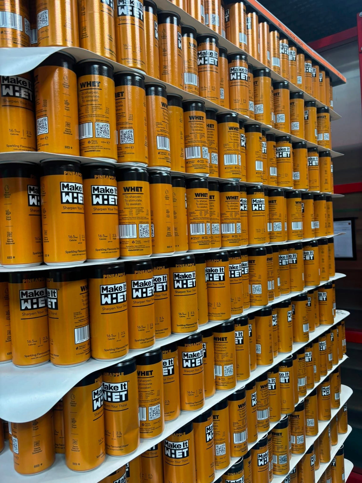 Rows of yellow Make It WHET cans on the production line