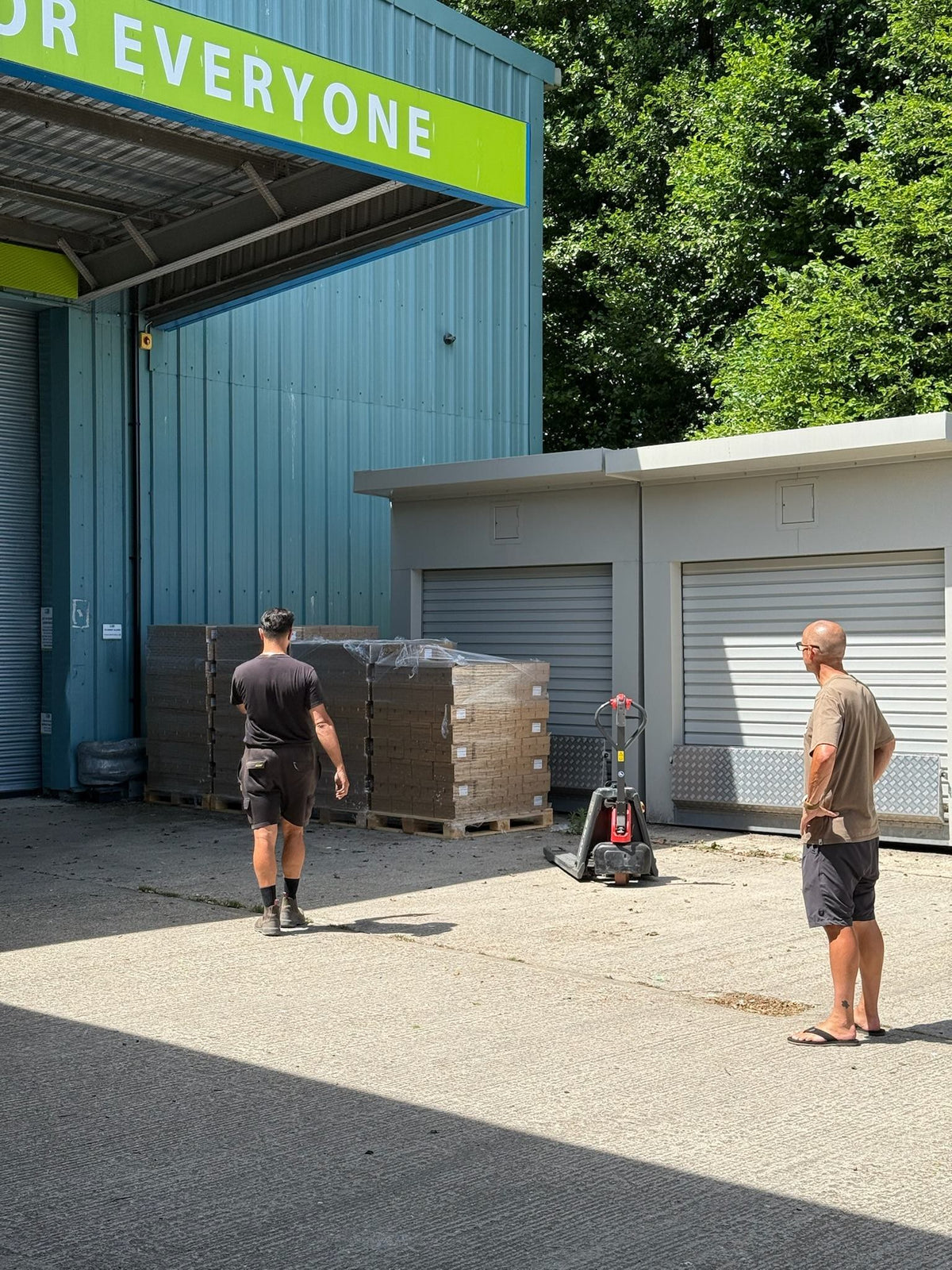A pallet of boxed cans being moved outside a storage building