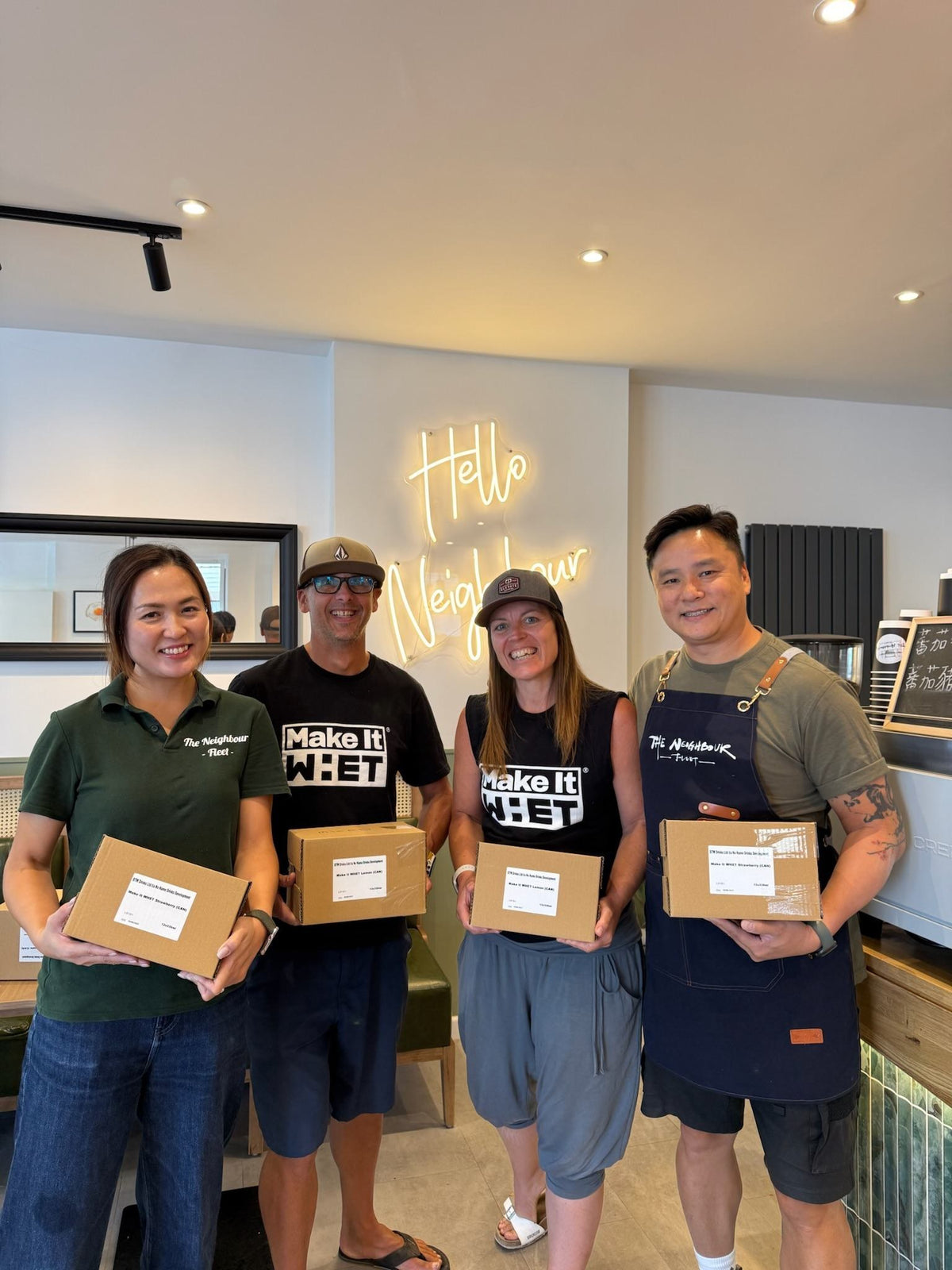 Four people holding boxes of Make It WHET